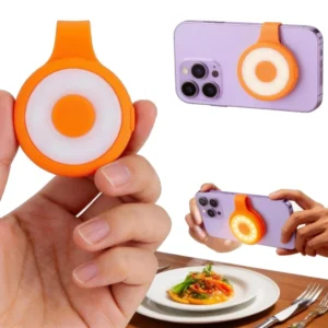 Magnetic mini keychain flashlight in orange with its fill light on, held in a hand and magnetised to a phone
