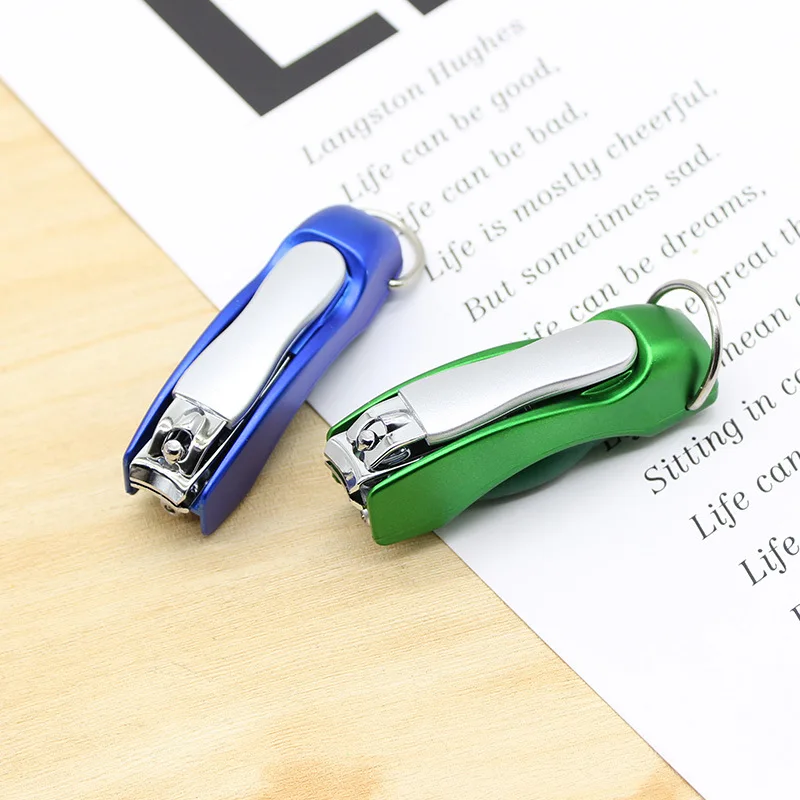 Blue and green multifunction pen keychains side by side on a notebook, each with its nail clipper folded open