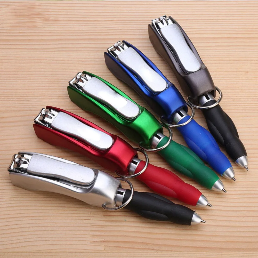 Five multifunction pen keychains in red, green, blue, grey and black laid out on a wooden desk, each showing its folding nail clipper and ballpoint tip