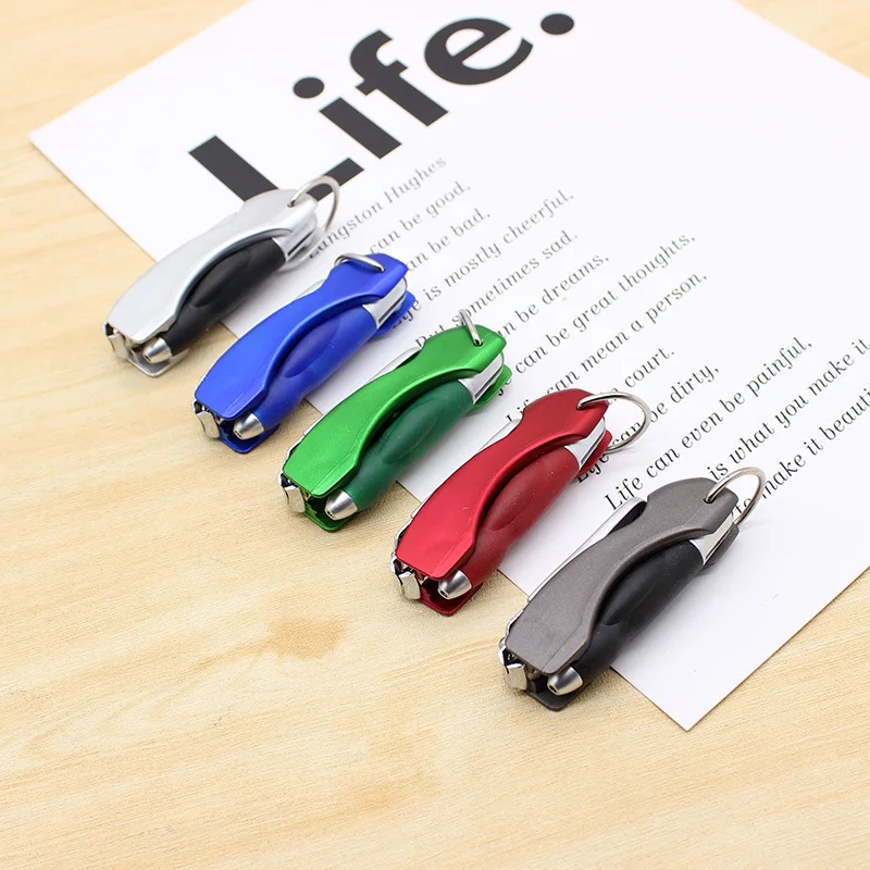 Five multifunction pen keychains fanned out across an open notebook, clippers folded shut and key rings attached