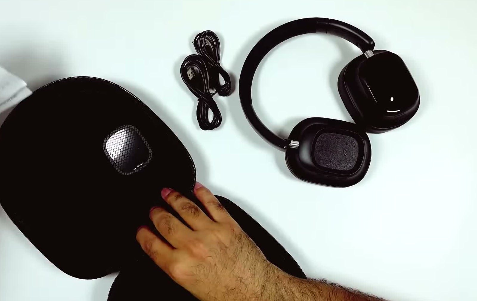 The unboxed contents laid out on a white surface: the hard carry case, the charging cable and the folded headphones