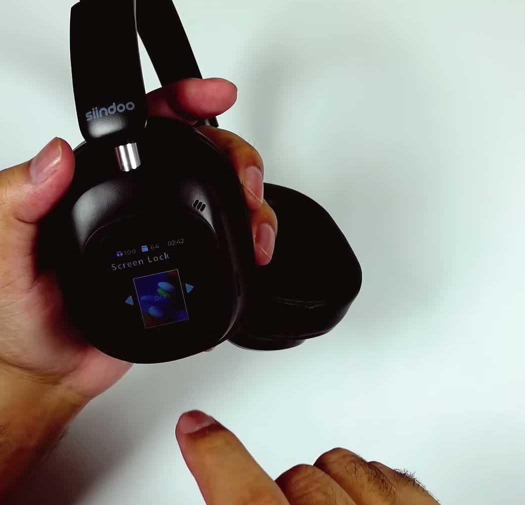 Close-up of the earcup held in hand showing the colour LED screen on its screen-lock display and the branding on the headband