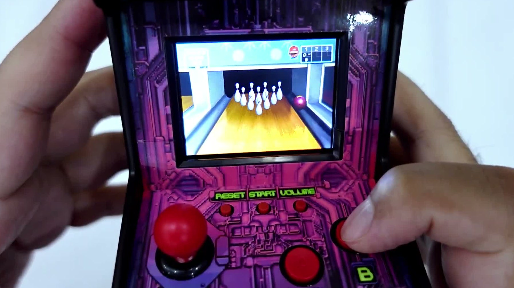 Close-up of the red 8-way joystick and arcade buttons with a bowling game running on the screen above