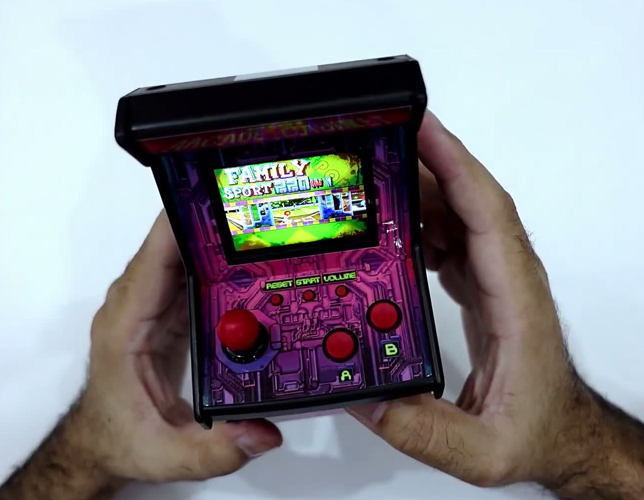 The actual pink Arcade Cabinet mini console held in both hands with a game menu on its colour screen