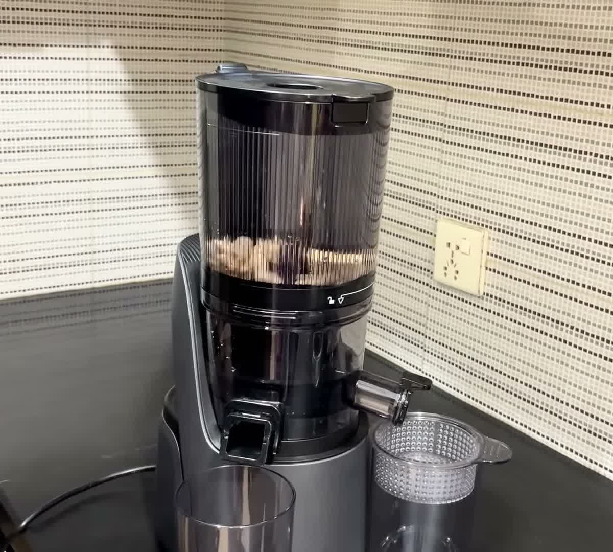 Canoly C16 cold press juicer set up on a kitchen counter with its pulp strainer beside it
