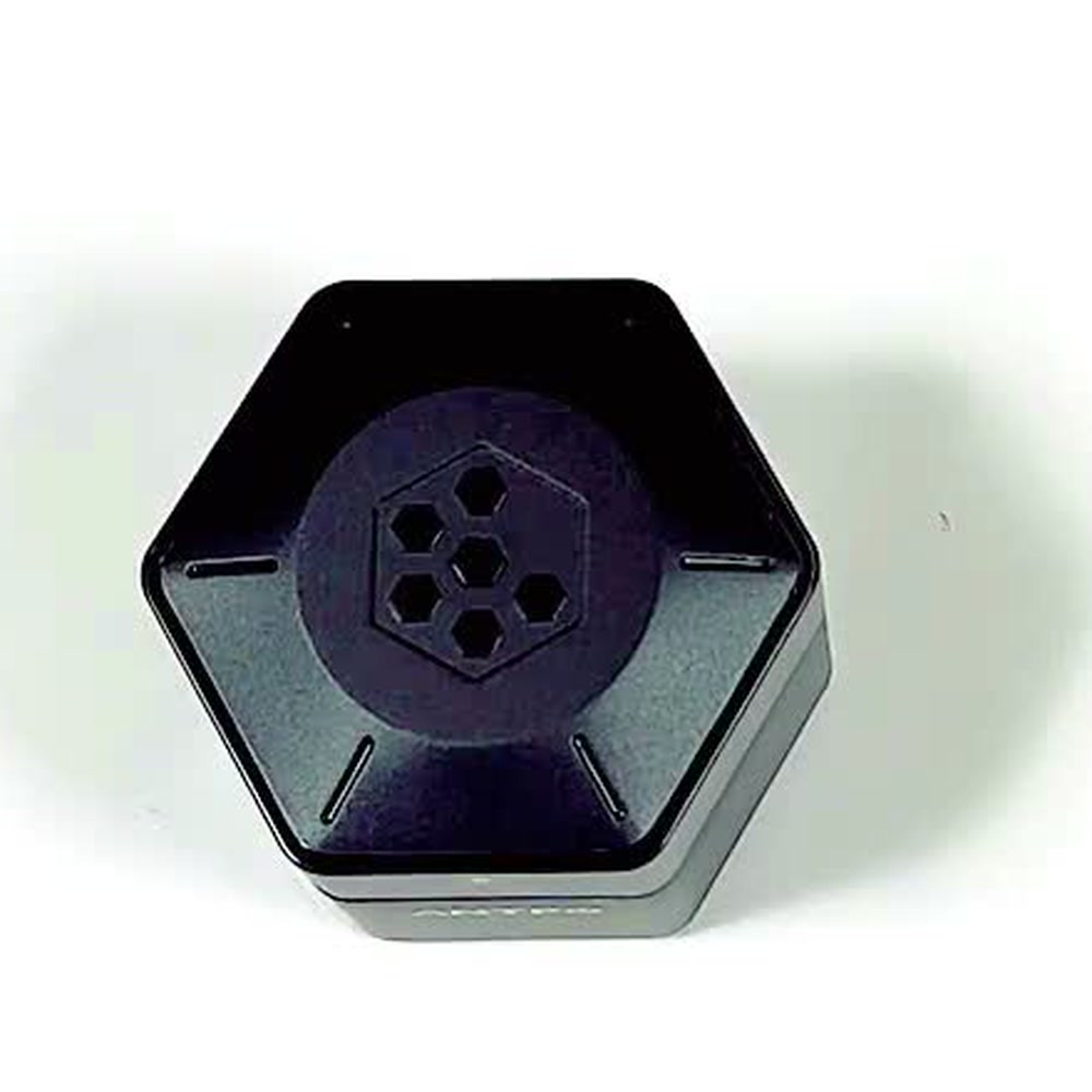 The closed hexagonal charging case photographed on a plain white surface, showing its compact size and lid catch