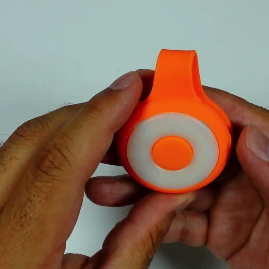 The actual magnetic mini keychain flashlight from the review, held face-on between two fingers