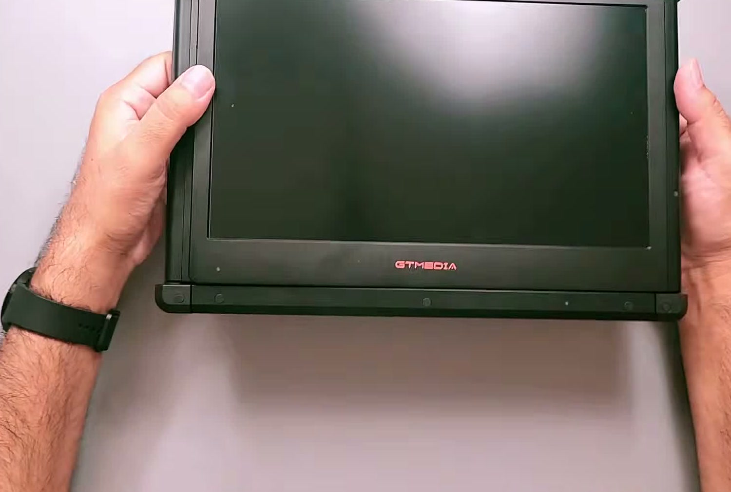 The GTMEDIA Mate X held in two hands, folded shut, showing the black panel and the GTMEDIA logo