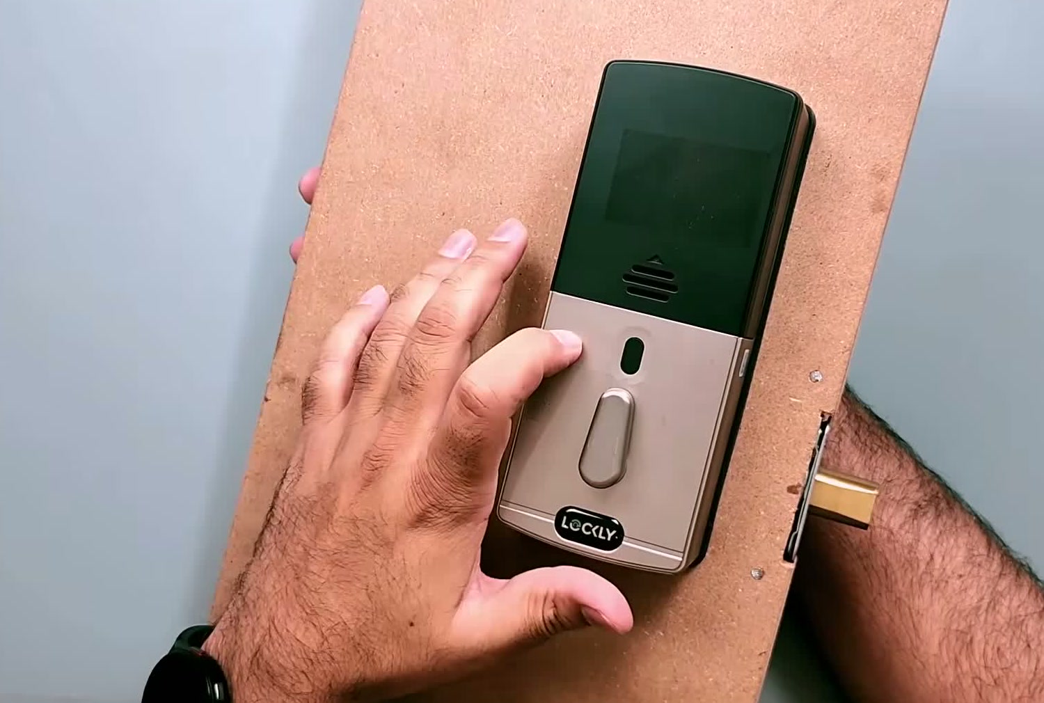 The Lockly Flex Touch interior module mounted on a test door, showing its dark face and thumbturn