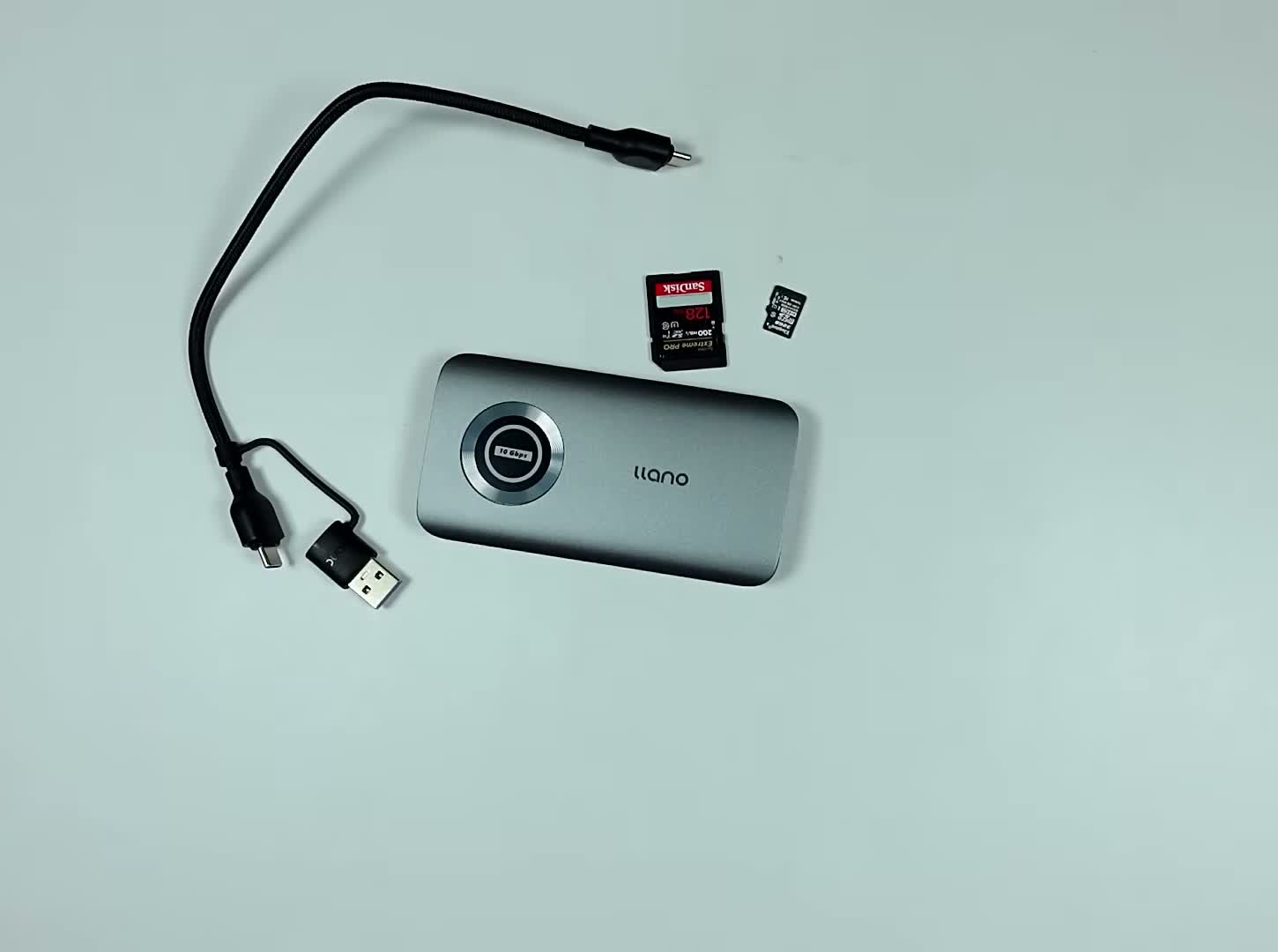 llano CFexpress card reader on a white desk with its USB-C cable, an SD card and a microSD card