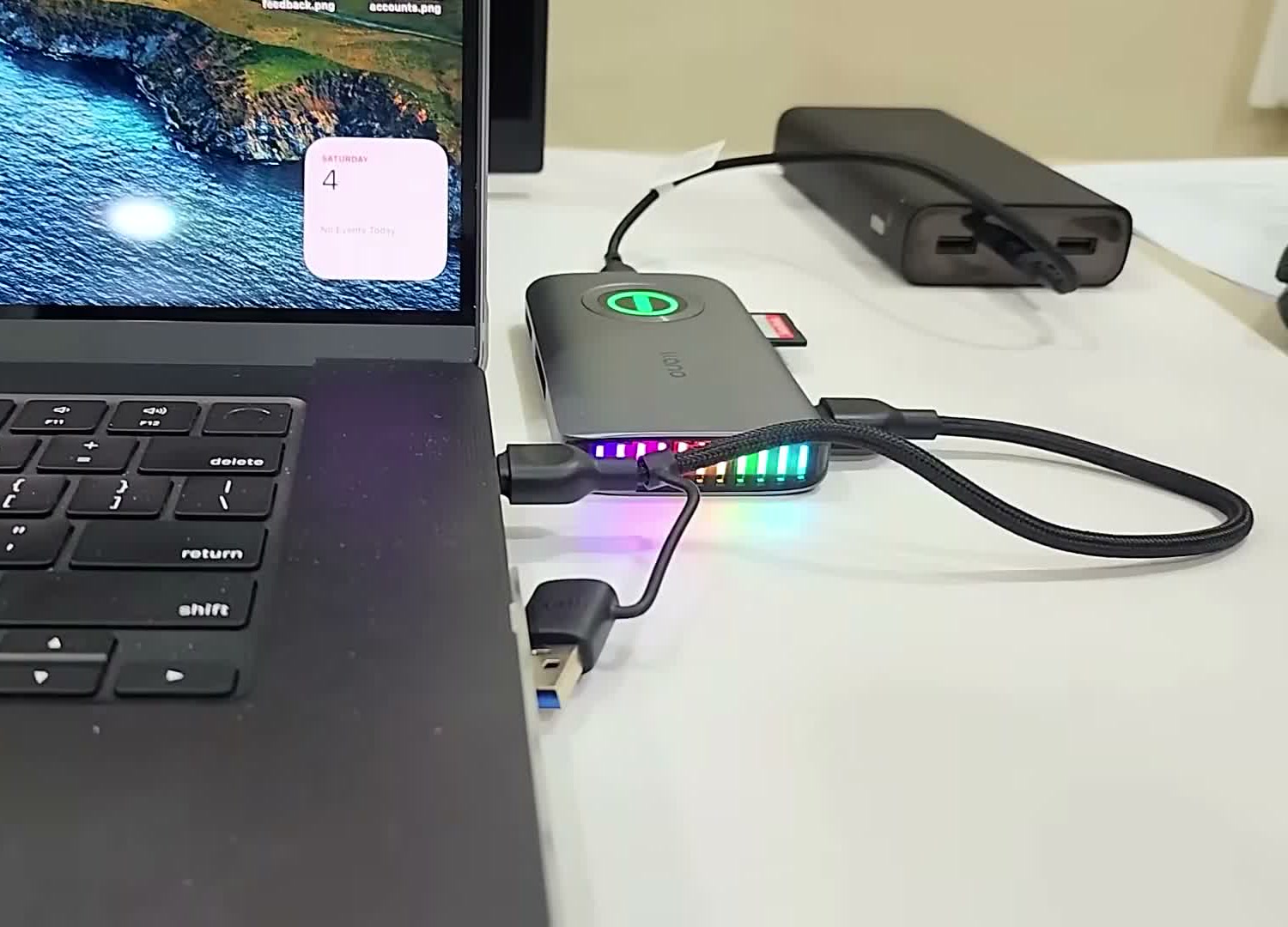 llano card reader connected to a MacBook by USB-C, its RGB strip lit, during a card offload