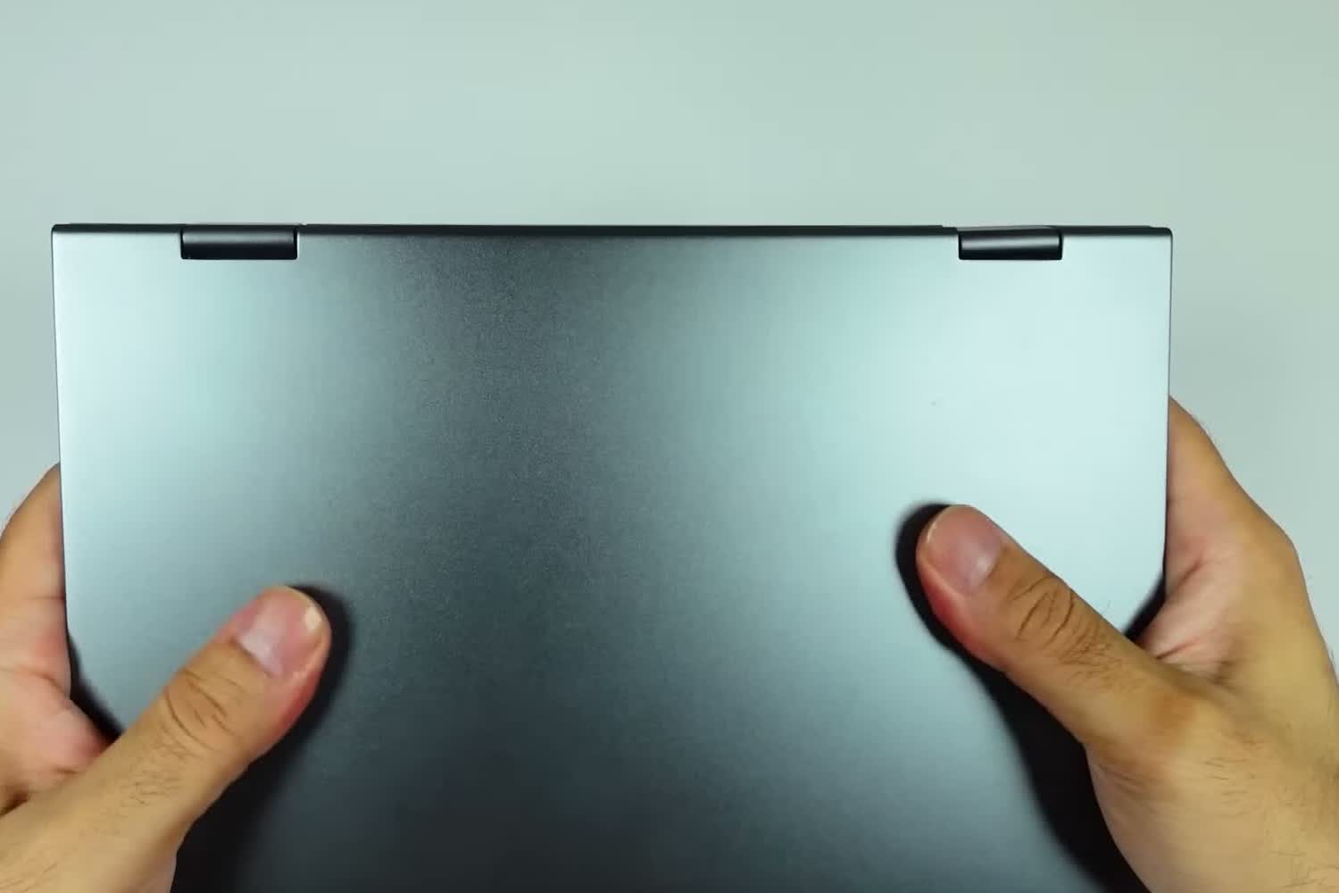 The actual CHUWI MiniBook X held closed in both hands during the review