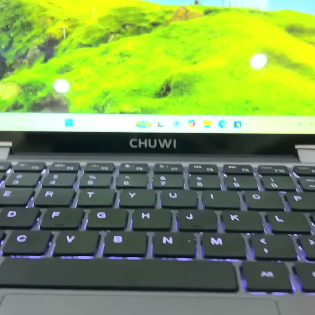 The MiniBook X backlit keyboard lit up, with the 2K touchscreen open above it