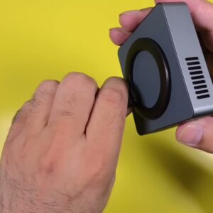 The Mars M1 Mini projector held in one hand, showing the lens ring and the side ventilation grille
