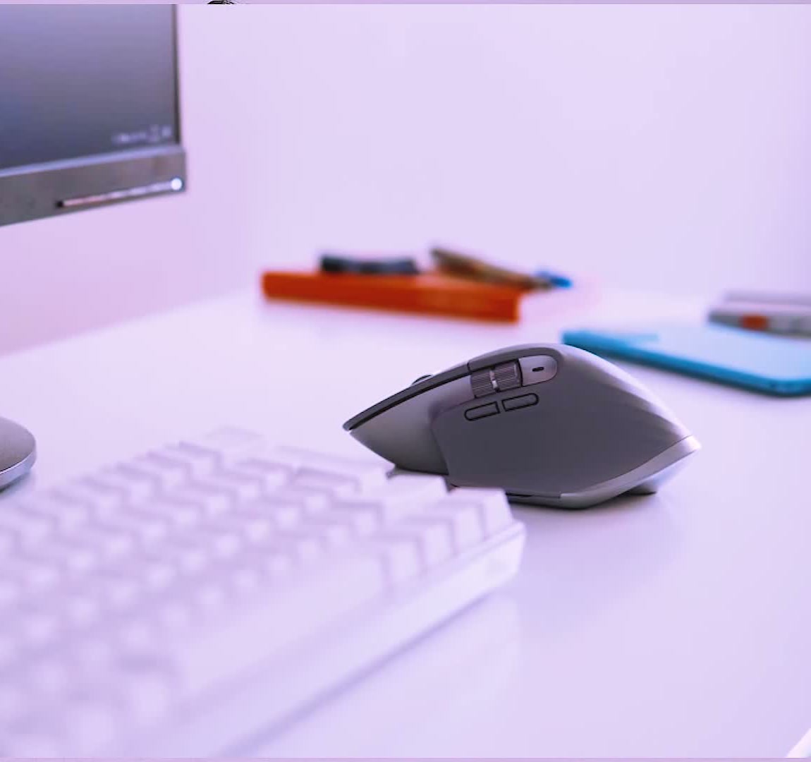 Logitech MX Master 3 on a white desk beside a keyboard and monitor, showing its size in a real setup