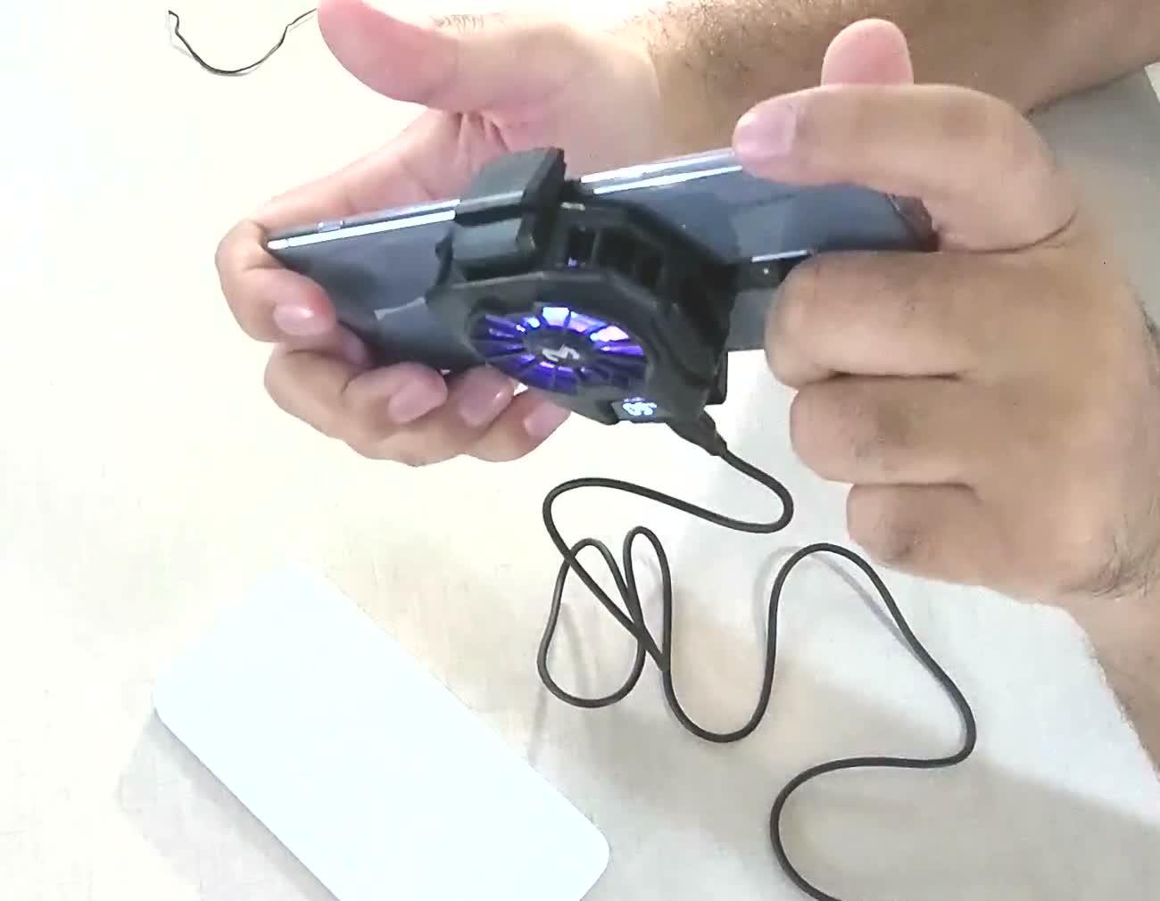 A phone held in both hands in landscape with the Memo cooler clipped to its back