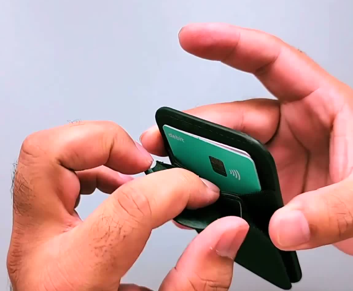 A contactless bank card being pushed out of the PUNCUBE wallet's elastic card slot