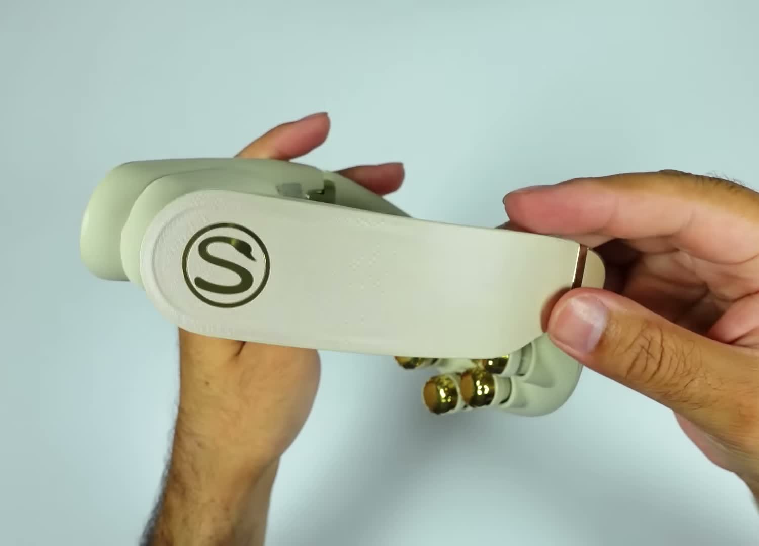 SKG G7 Pro Fold 3.0 neck massager held in both hands, showing the SKG logo on the cream body