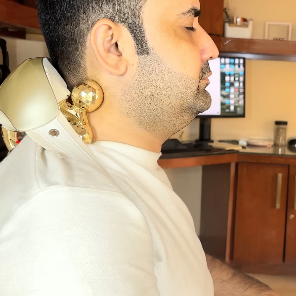 Man wearing the cream SKG H7 Ultra E neck massager hands-free over his shoulders, a gold kneading node resting against the side of his neck