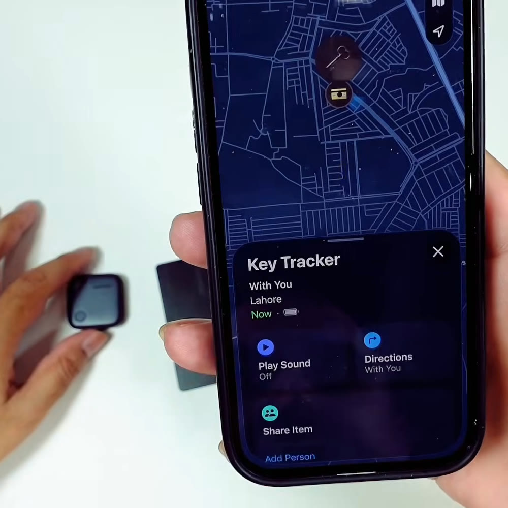 UGREEN FineTrack tracker tag beside an iPhone showing it live in Apple Find My as Key Tracker, located in Lahore