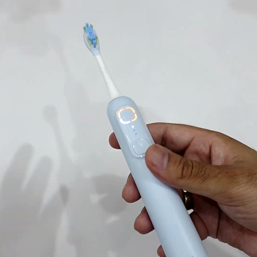 Real photo of the blue MIJIA toothbrush in hand with its reminder ring lit, from the Gadget Hunting with RR review