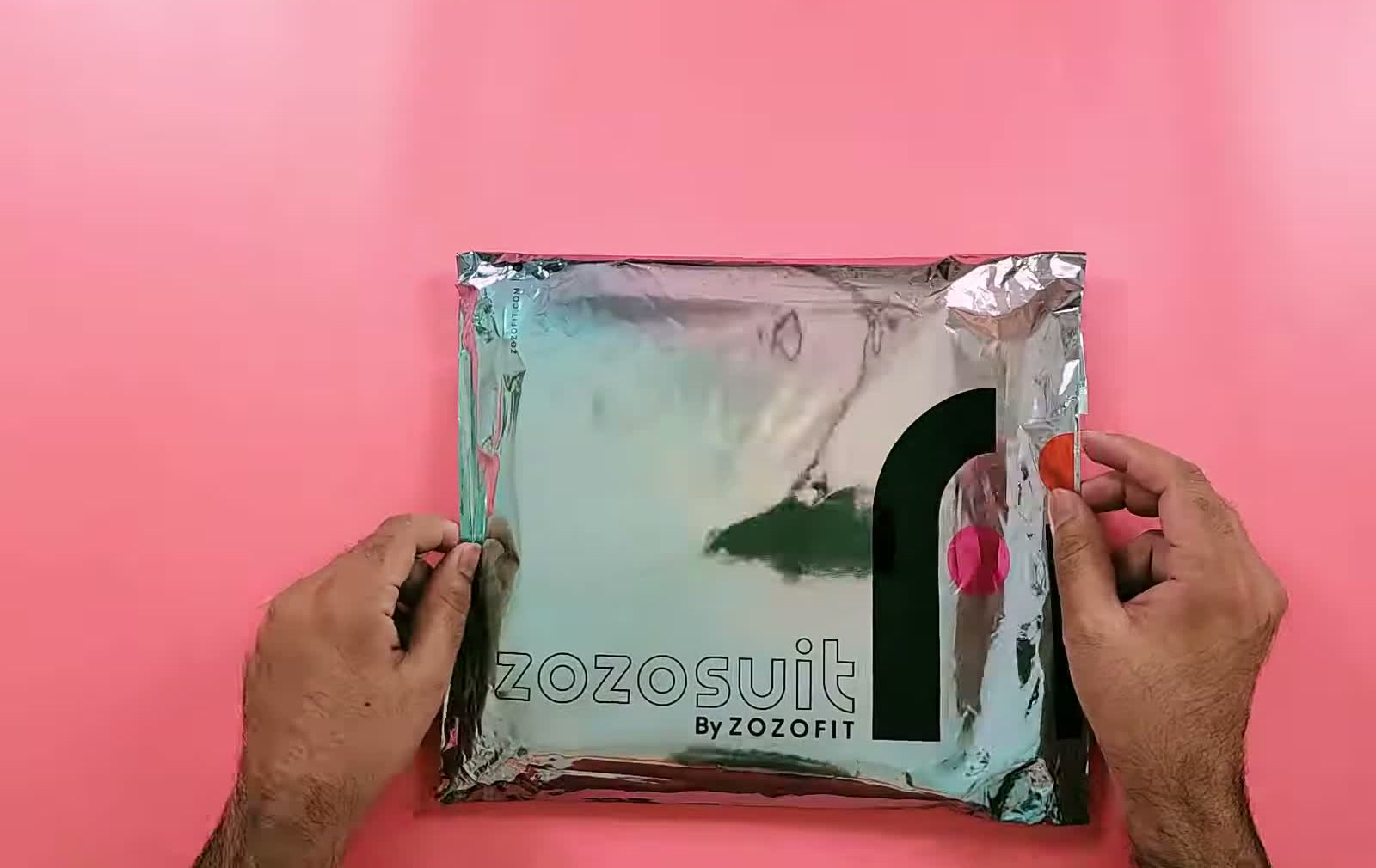 The sealed zozosuit by ZOZOFIT retail pouch held in both hands, showing the branded front of the pack